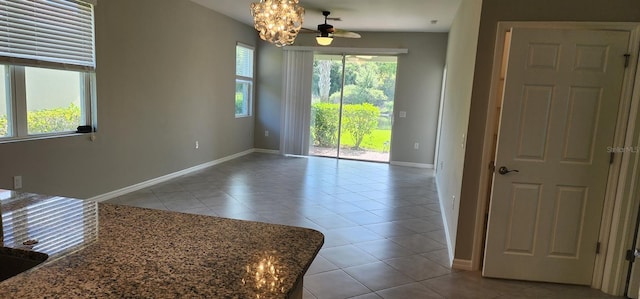 unfurnished room with light tile patterned floors, a ceiling fan, and baseboards