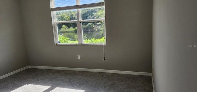 spare room with plenty of natural light, a water view, and baseboards