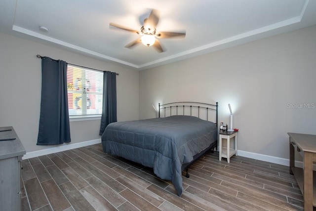 bedroom featuring dark hardwood / wood-style floors, a raised ceiling, and ceiling fan