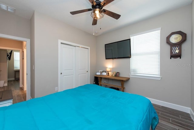 bedroom featuring multiple windows, a closet, ceiling fan, and dark wood-type flooring