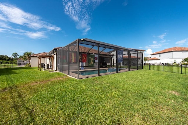 rear view of property featuring a lanai, a yard, and a fenced in pool