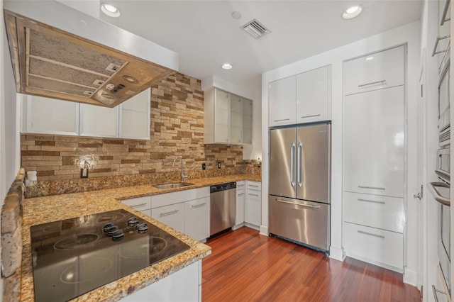 kitchen with appliances with stainless steel finishes, tasteful backsplash, sink, white cabinets, and dark hardwood / wood-style flooring