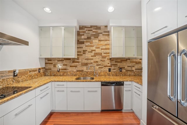 kitchen with sink, tasteful backsplash, light stone counters, appliances with stainless steel finishes, and white cabinets