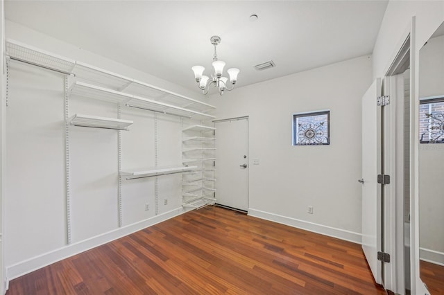 spacious closet with an inviting chandelier and dark hardwood / wood-style flooring