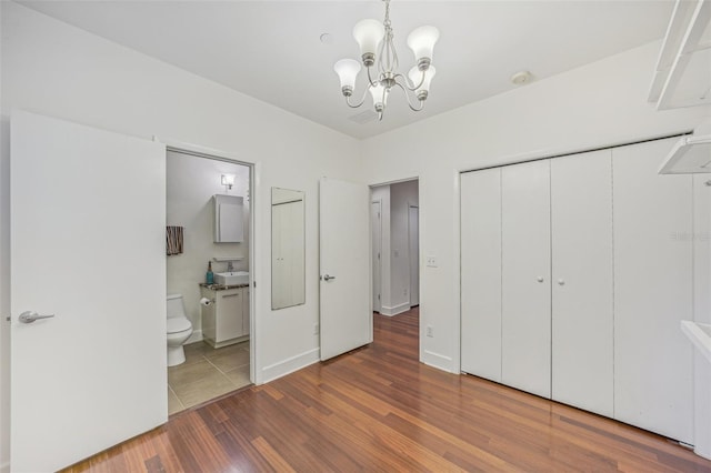 unfurnished bedroom with dark hardwood / wood-style flooring, a closet, a chandelier, and ensuite bathroom