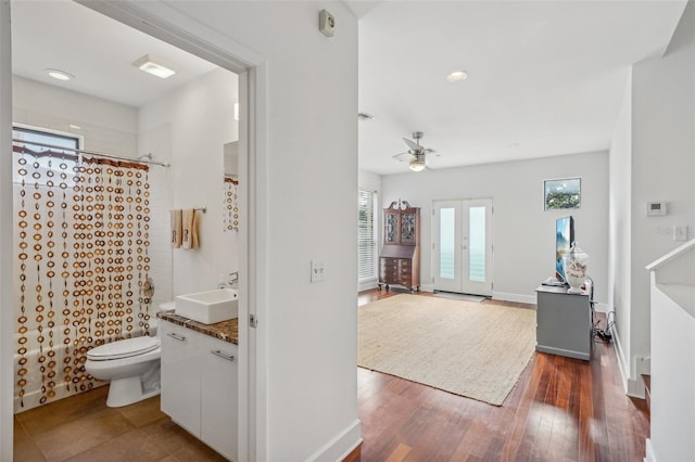 full bathroom featuring shower / tub combo with curtain, hardwood / wood-style flooring, vanity, french doors, and toilet