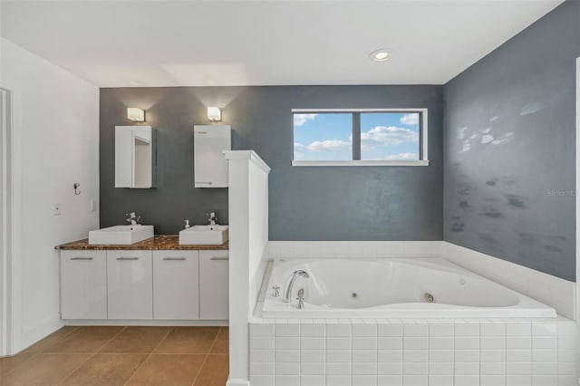 bathroom with tile patterned flooring, vanity, and a relaxing tiled tub