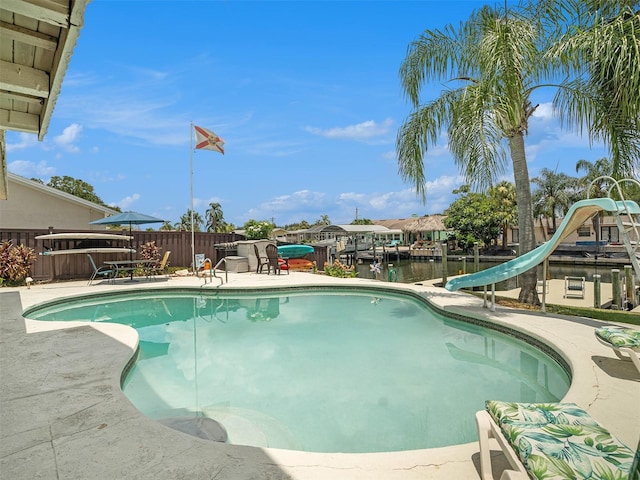 view of pool with a water view, a patio area, and a water slide