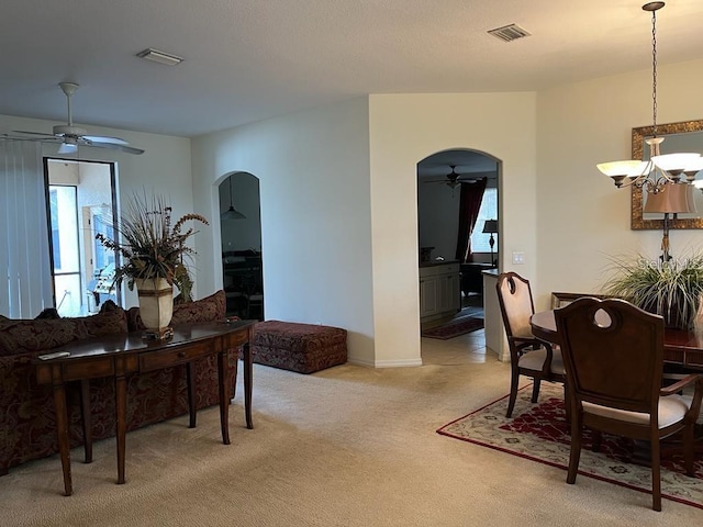 dining room with light colored carpet and ceiling fan with notable chandelier