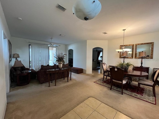 carpeted dining space featuring ceiling fan with notable chandelier