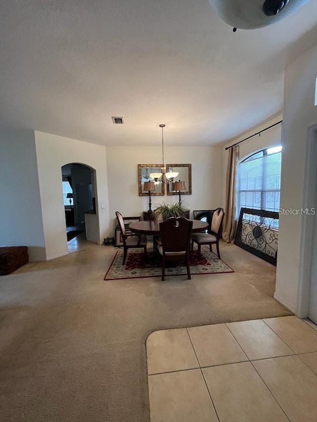 dining area with a chandelier and light carpet