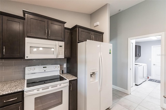 kitchen featuring white appliances, backsplash, washing machine and dryer, light stone counters, and dark brown cabinetry