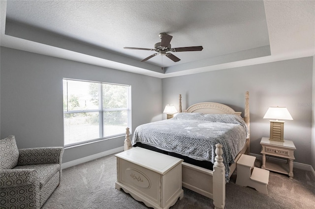 carpeted bedroom featuring ceiling fan, a textured ceiling, and a tray ceiling