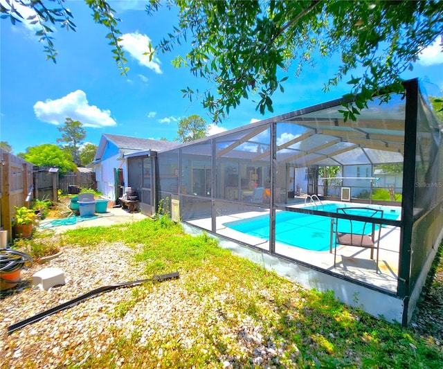 back of property featuring a fenced in pool, glass enclosure, and a patio