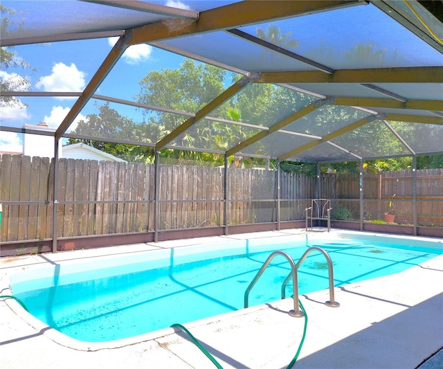 view of pool with glass enclosure and a patio