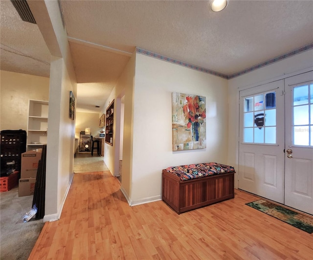 entryway with a textured ceiling, light hardwood / wood-style flooring, and french doors