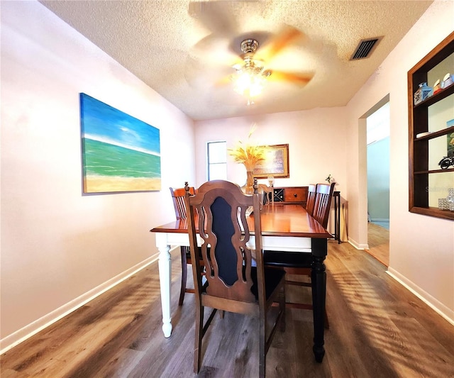 dining space featuring ceiling fan, dark wood-type flooring, and a textured ceiling