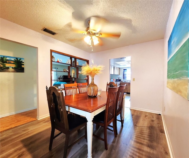 dining area with a textured ceiling, ceiling fan, and hardwood / wood-style floors