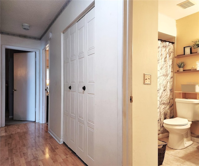 hall with a textured ceiling and light hardwood / wood-style floors