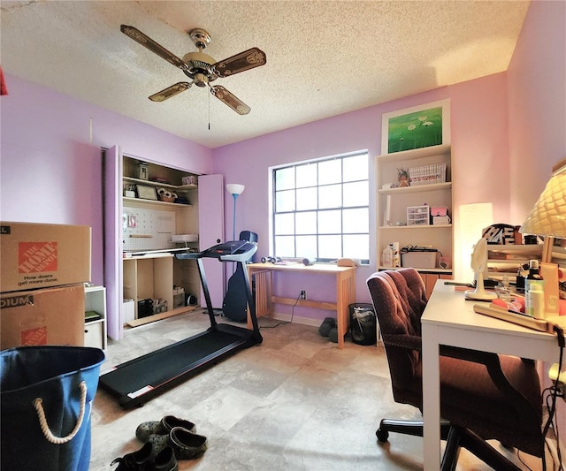 exercise room with ceiling fan and a textured ceiling