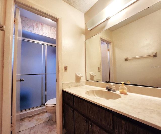 bathroom with a textured ceiling, toilet, a shower with door, and vanity