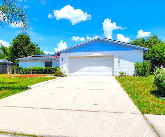 single story home with brick siding, concrete driveway, an attached garage, a front yard, and fence