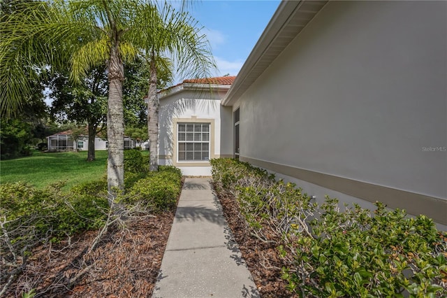 property entrance with a yard, a tiled roof, and stucco siding