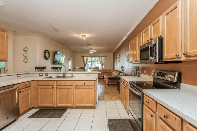 kitchen featuring stainless steel appliances, light countertops, open floor plan, a sink, and a peninsula