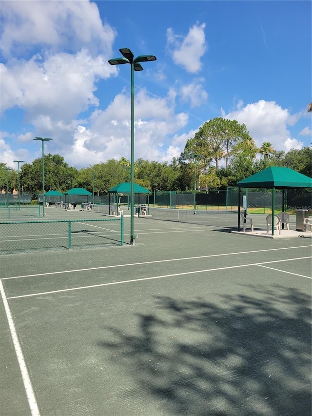 view of tennis court featuring fence and a gazebo