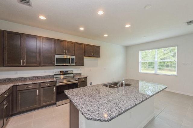 kitchen featuring sink, a kitchen island with sink, light tile patterned floors, stainless steel appliances, and light stone countertops