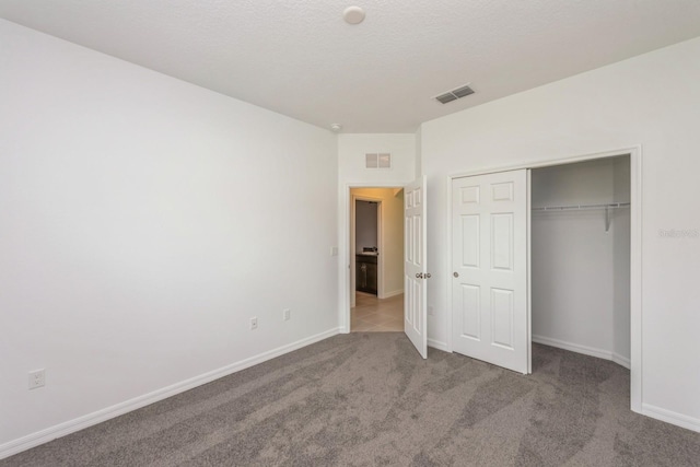 unfurnished bedroom featuring a closet, a textured ceiling, and carpet