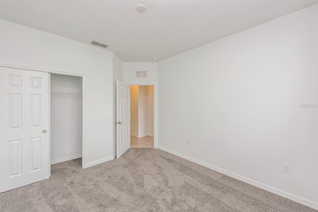 unfurnished bedroom with light colored carpet and a closet