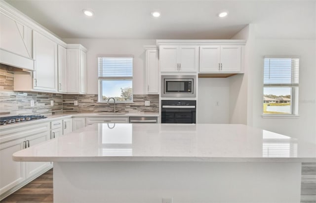 kitchen with stainless steel appliances, light stone countertops, sink, and white cabinets