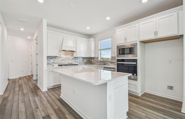 kitchen featuring stainless steel appliances, a center island, sink, and white cabinets