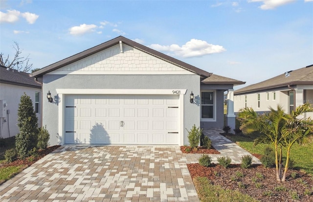 single story home featuring decorative driveway, an attached garage, and stucco siding