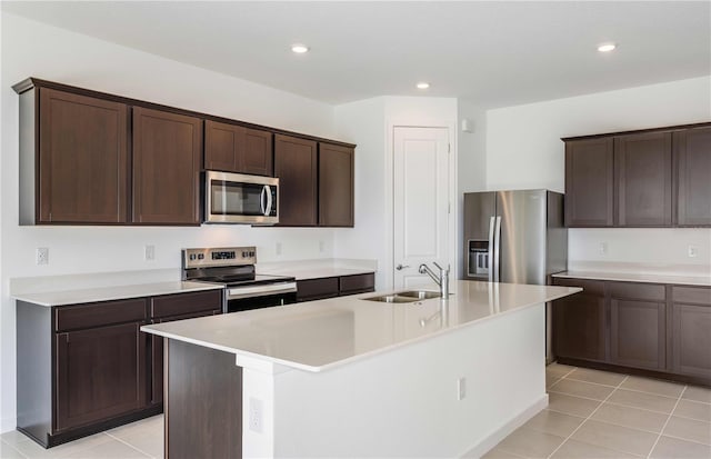 kitchen with a kitchen island with sink, sink, light tile patterned floors, and appliances with stainless steel finishes