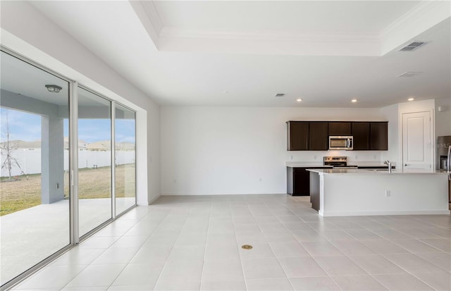 kitchen featuring an island with sink, sink, a tray ceiling, stainless steel appliances, and crown molding