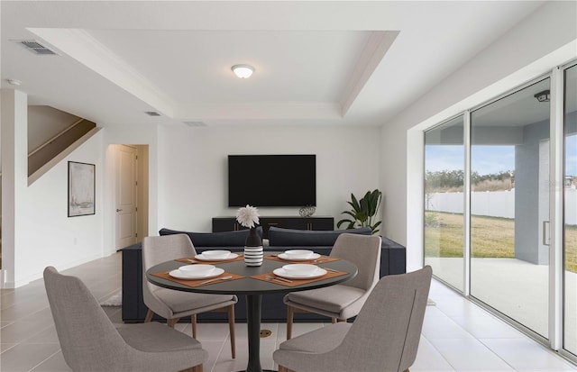 tiled dining space featuring a raised ceiling