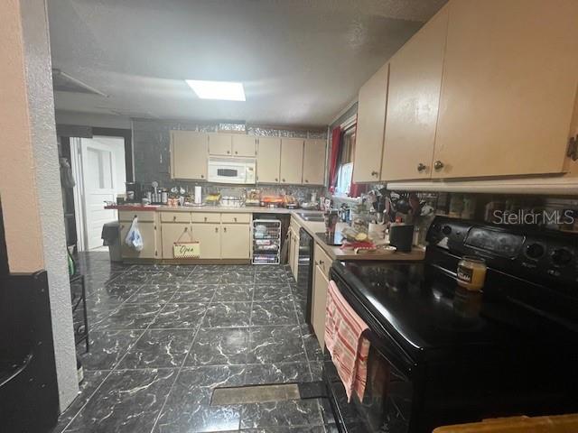 kitchen featuring black appliances, sink, wine cooler, and cream cabinets