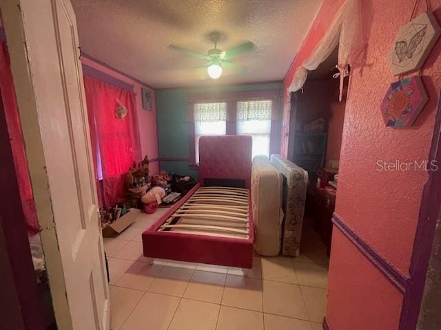 tiled bedroom with ceiling fan and a textured ceiling