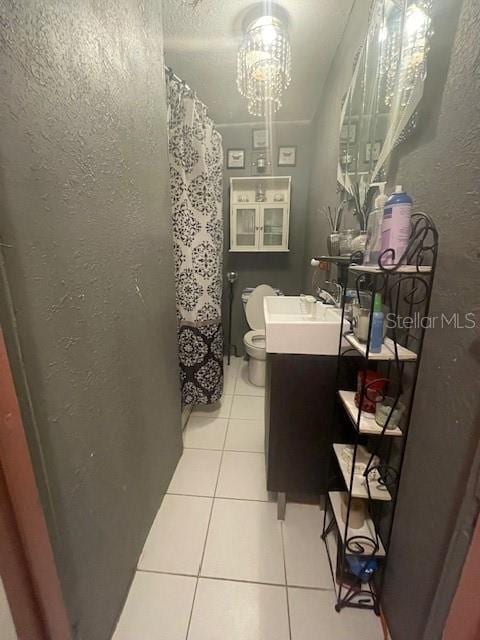 bathroom with tile patterned flooring, vanity, toilet, and a notable chandelier