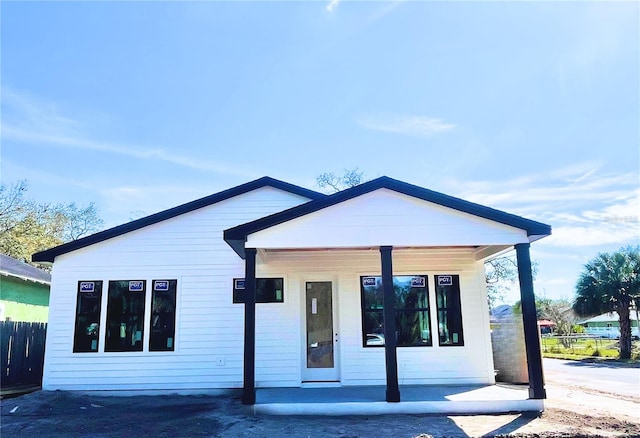 view of front facade featuring covered porch and fence