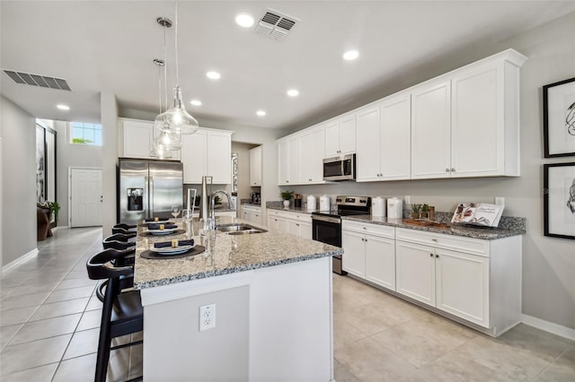 kitchen featuring sink, stainless steel appliances, pendant lighting, a kitchen island with sink, and white cabinets