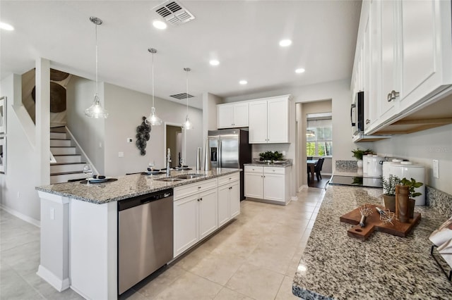 kitchen featuring appliances with stainless steel finishes, sink, white cabinetry, and an island with sink