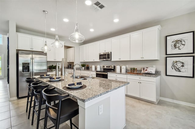 kitchen with white cabinetry, sink, hanging light fixtures, an island with sink, and appliances with stainless steel finishes