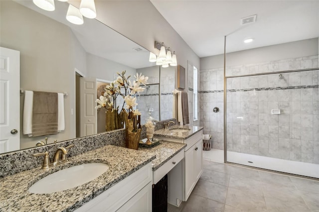 bathroom featuring tile patterned floors, vanity, and a tile shower