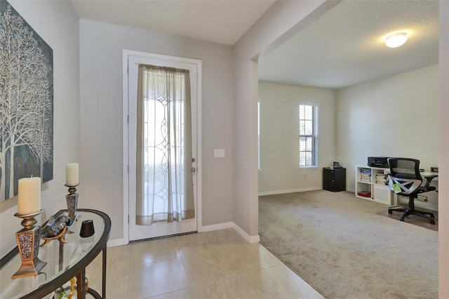 tiled entryway featuring baseboards and carpet flooring