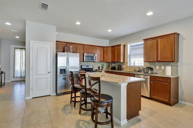 kitchen featuring a kitchen breakfast bar, a center island, stainless steel appliances, and tasteful backsplash