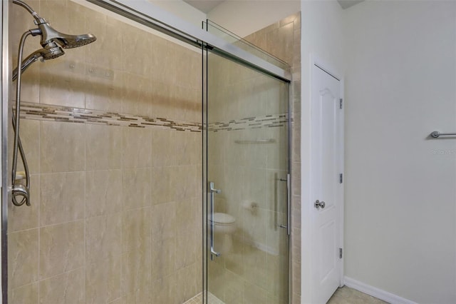 bathroom featuring toilet and a shower with shower door