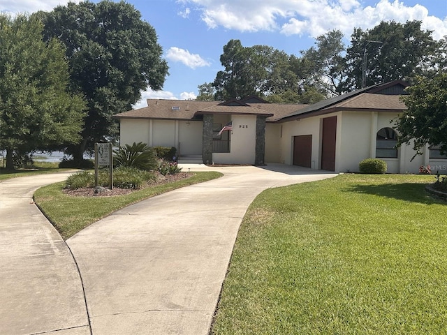 view of front of home featuring concrete driveway, a front lawn, and stucco siding